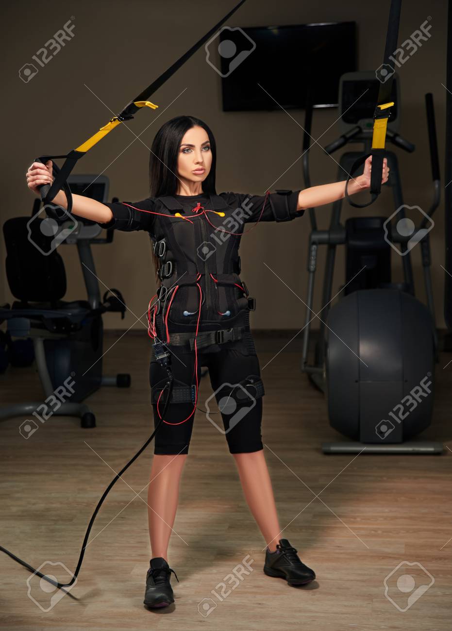 근육 근육 자극 소송에서 다시 및 Trx 현수막와 손을 운동에 갈색 머리 소녀. 빛나는 효과. 고딕 스타일. EMS. 로열티 무료  사진, 그림, 이미지 그리고 스톡포토그래피. Image 79800443