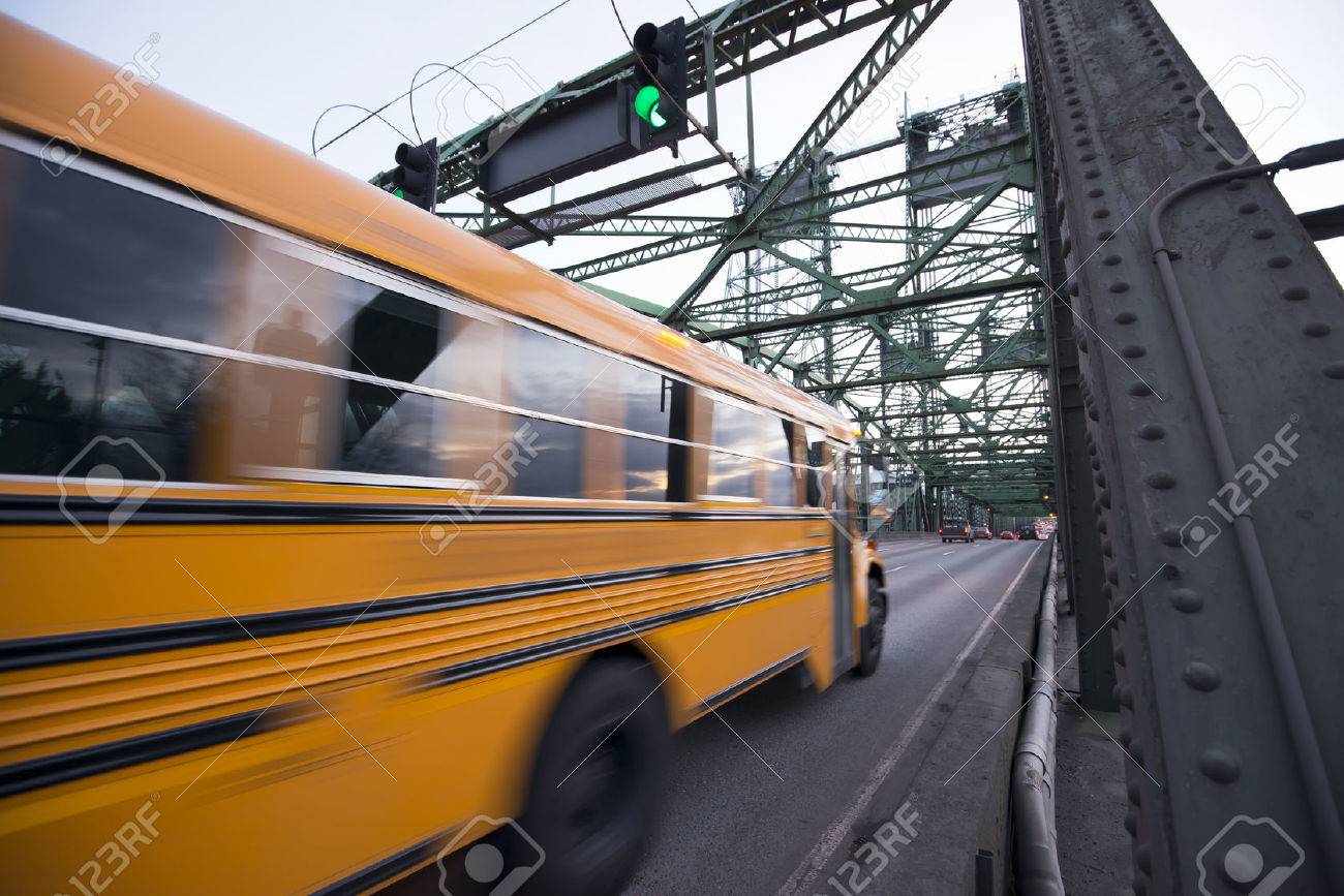 long blurred in motion yellow school bus moves on the metal truss