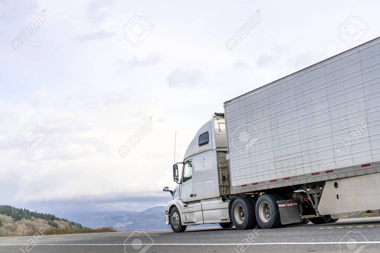 Powerful long haul big rig industrial grade diesel semi truck transporting commercial food cargo in refrigerated semi trailer running on the flat road with sky and hills view in Columbia Gorge - 141966561 Powerful long haul big rig industrial grade diesel semi truck transporting commercial food cargo in refrigerated semi trailer running on the flat road with sky and hills view in Columbia Gorge - 141966561