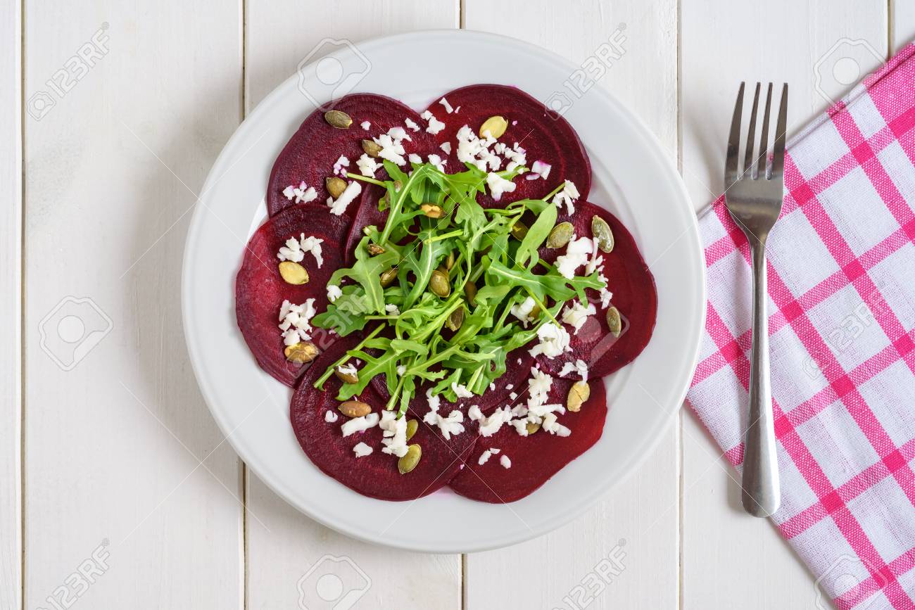 Beetroot carpaccio with rucola leaves and pumpkin seeds on wooden white background. - 92863577 Beetroot carpaccio with rucola leaves and pumpkin seeds on wooden white background. - 92863577