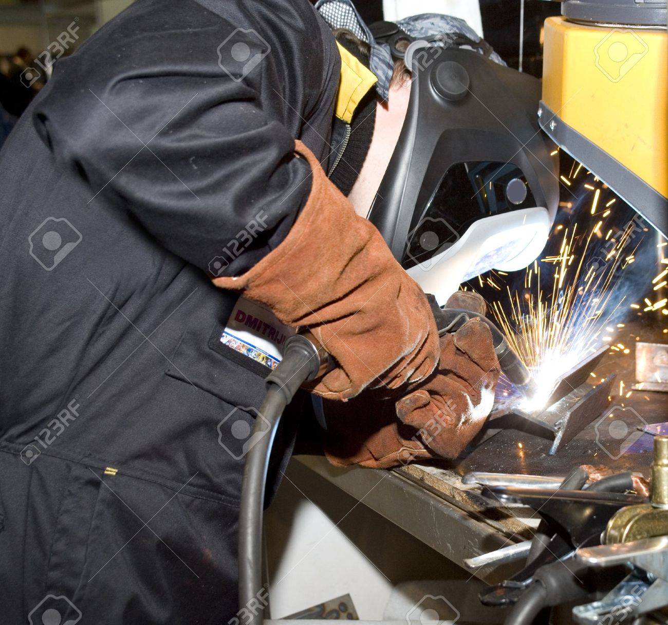 The welder in protective clothes behind job - 6005013 The welder in protective clothes behind job - 6005013