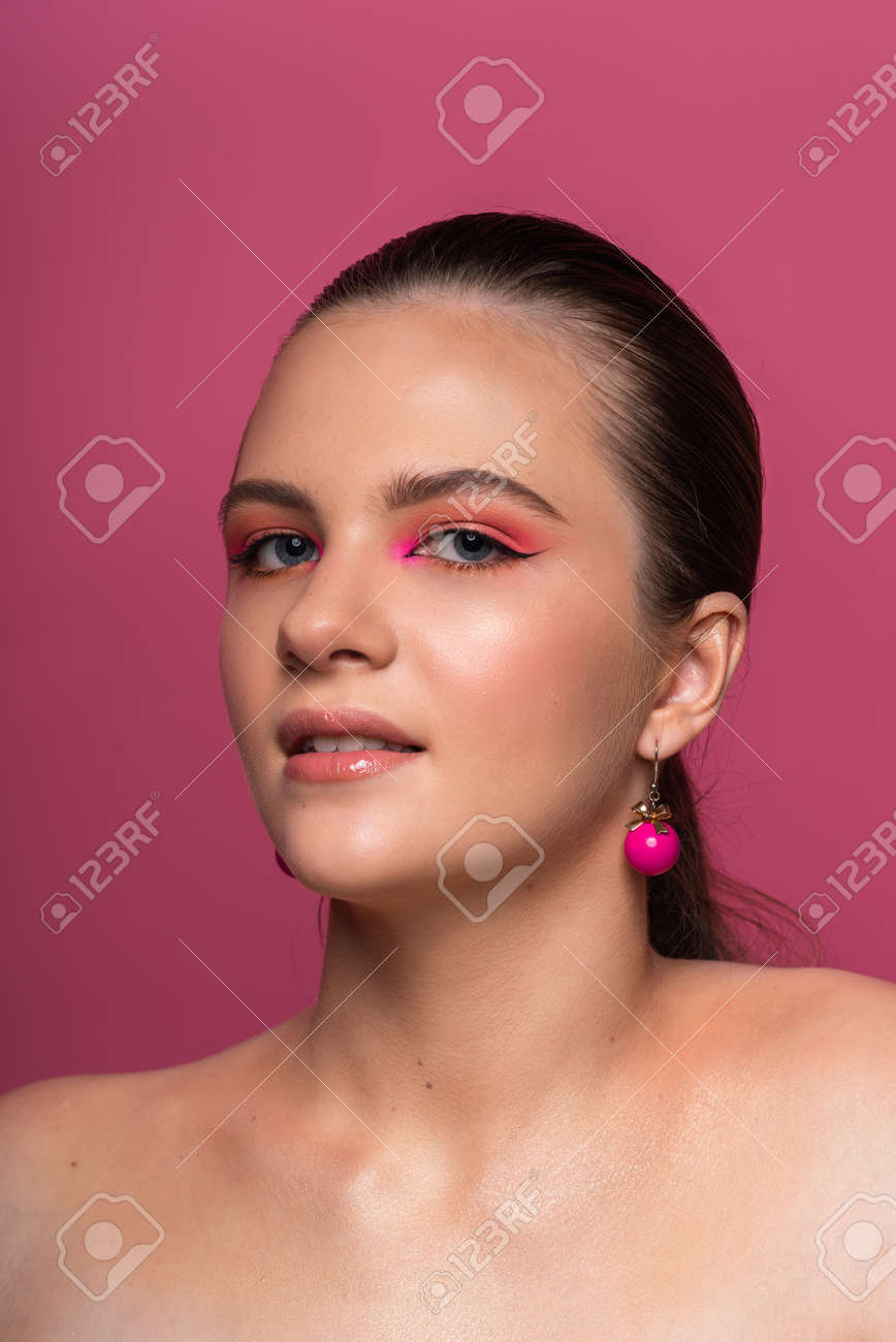 High beauty photo of a lovely young girl with blue eyes, round pink earrings and wonderful professional makeup, with long brown hair. Posing over rosy background. Close-up. Studio shot. Portrait - 167537011 High beauty photo of a lovely young girl with blue eyes, round pink earrings and wonderful professional makeup, with long brown hair. Posing over rosy background. Close-up. Studio shot. Portrait - 167537011