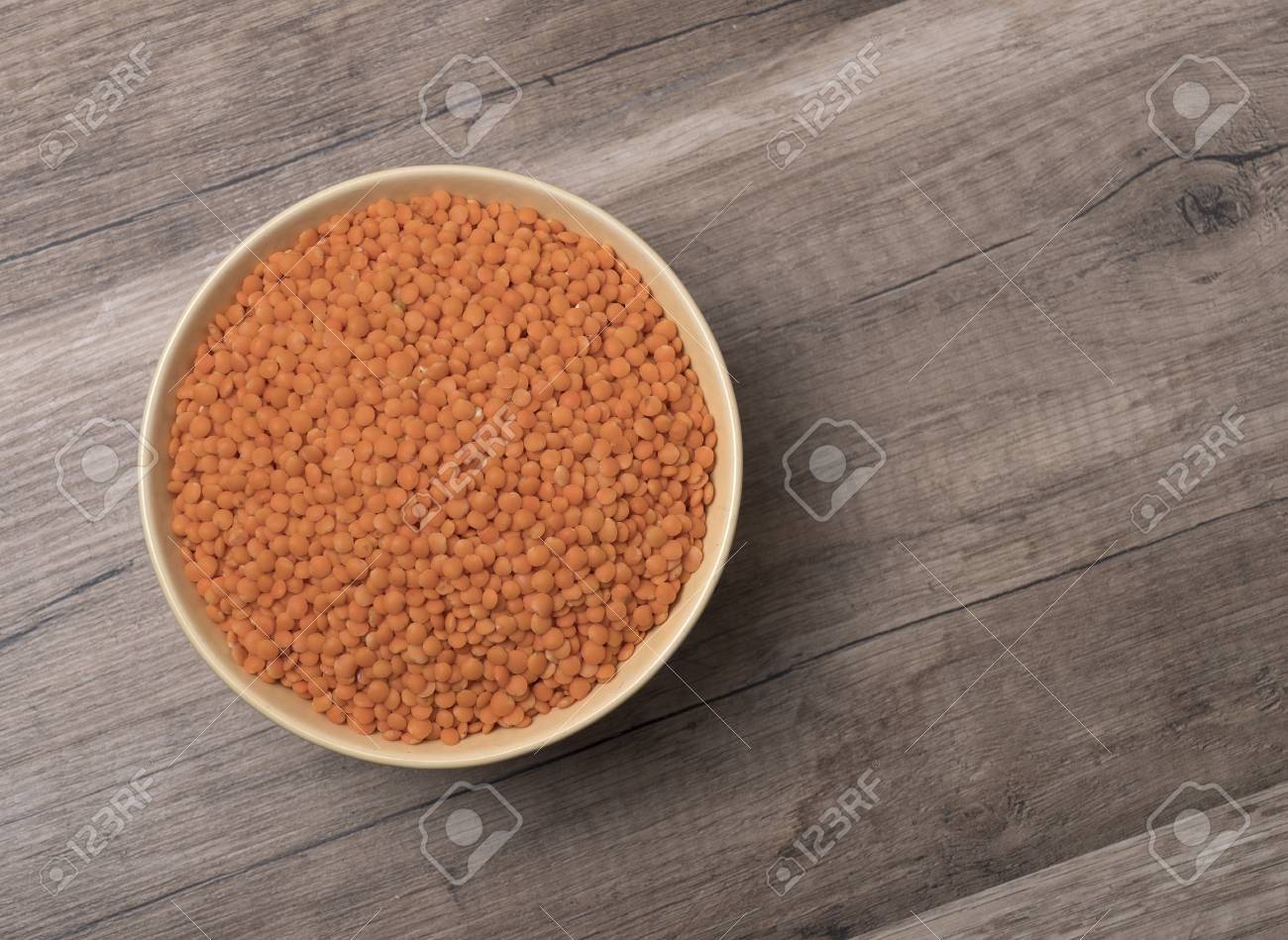 dry red lentils in a bowl on wooden background top view