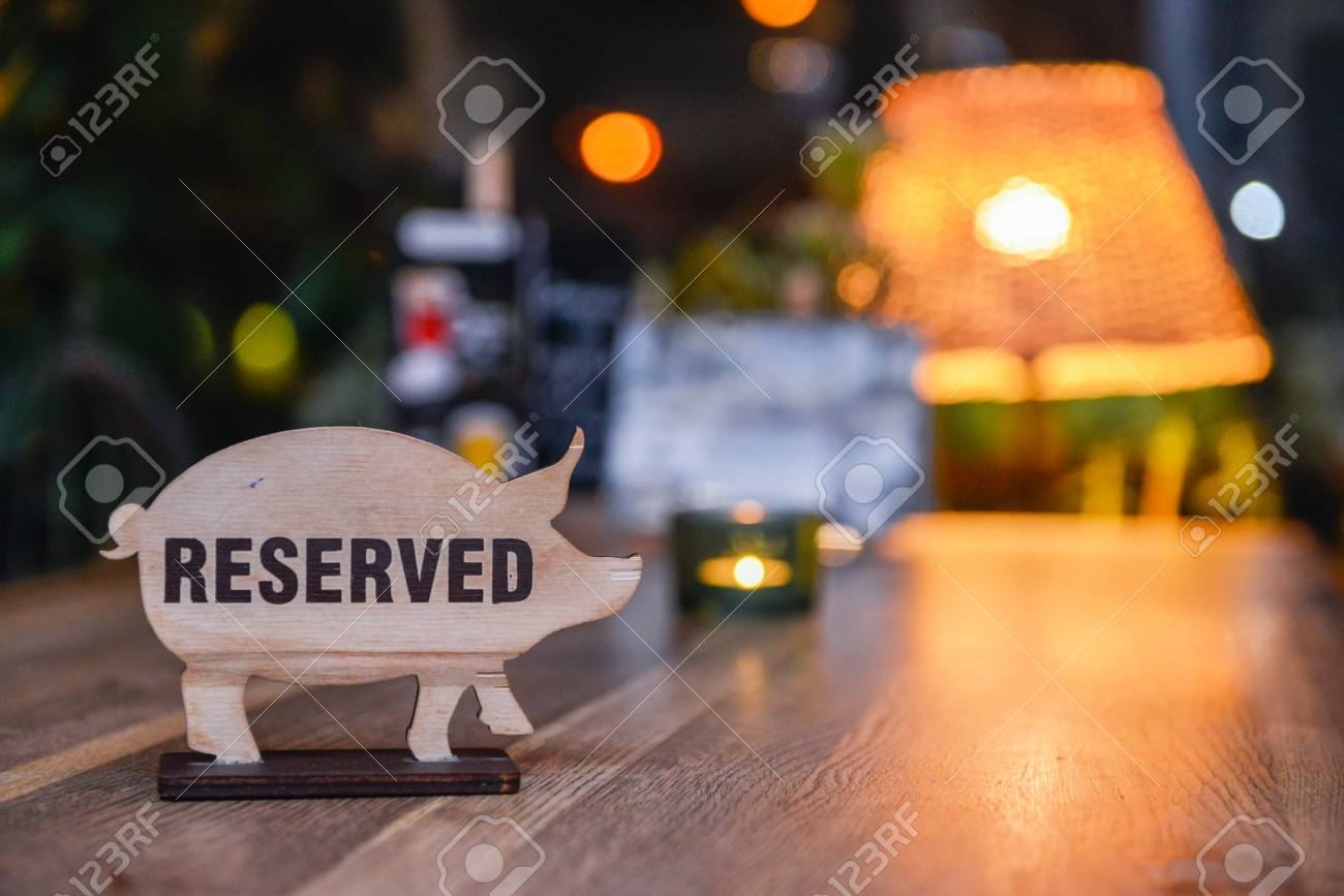Reserved sign on a restaurant table. Sign in the form of pigs - 97136235 Reserved sign on a restaurant table. Sign in the form of pigs - 97136235