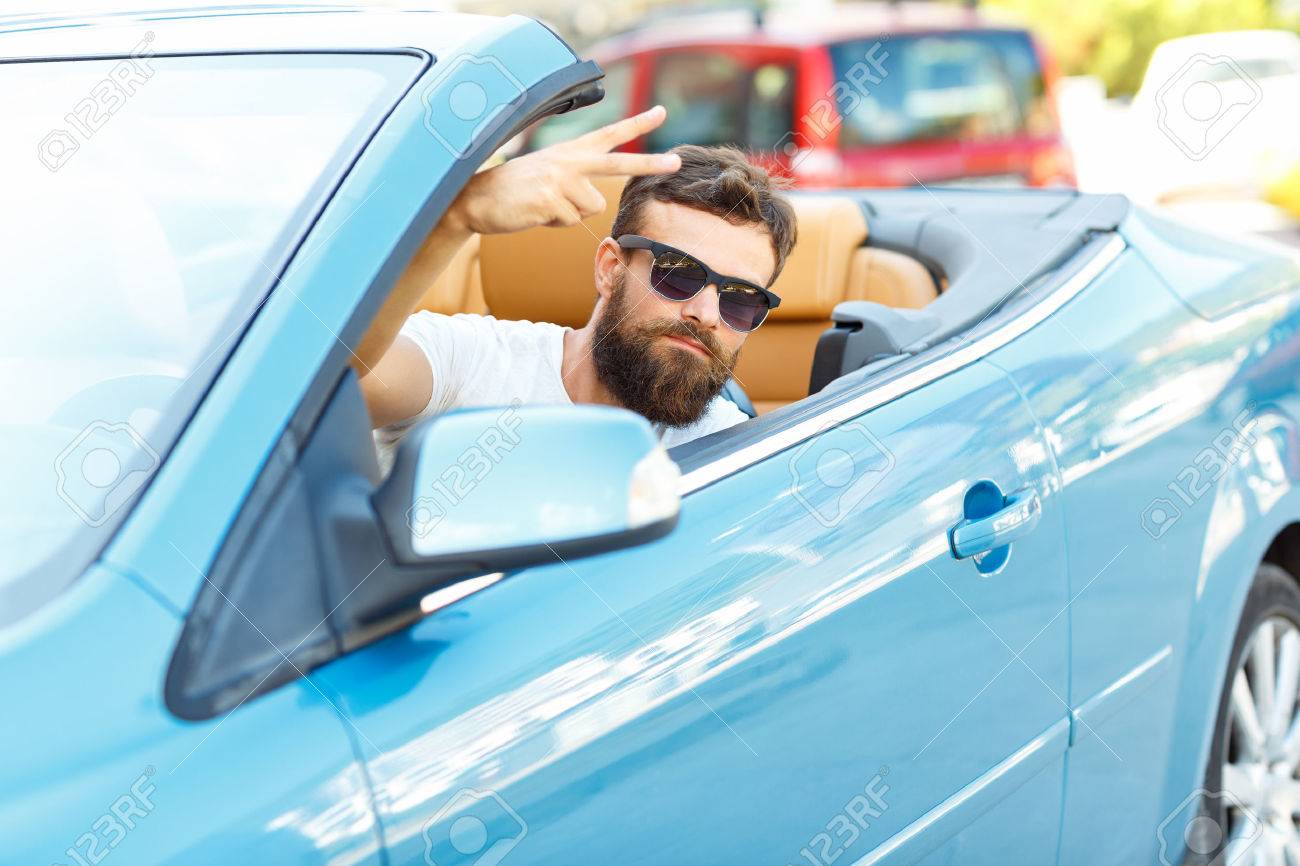 A young bearded man sitting in a convertible - - the concept of buying a used car or a rental car - 48229593 A young bearded man sitting in a convertible - - the concept of buying a used car or a rental car - 48229593
