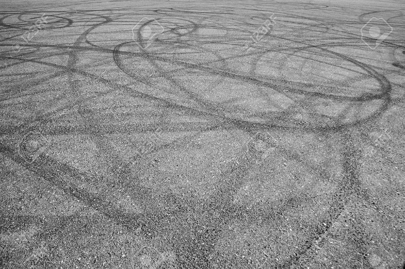 a bunch of random skid marks from cars in an empty asphalt parking