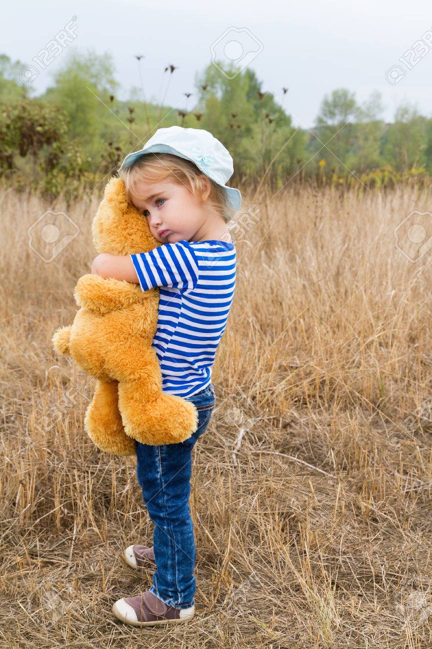 Cute little girl standing in the grass hugging a Teddy bear - 45662445 Cute little girl standing in the grass hugging a Teddy bear - 45662445