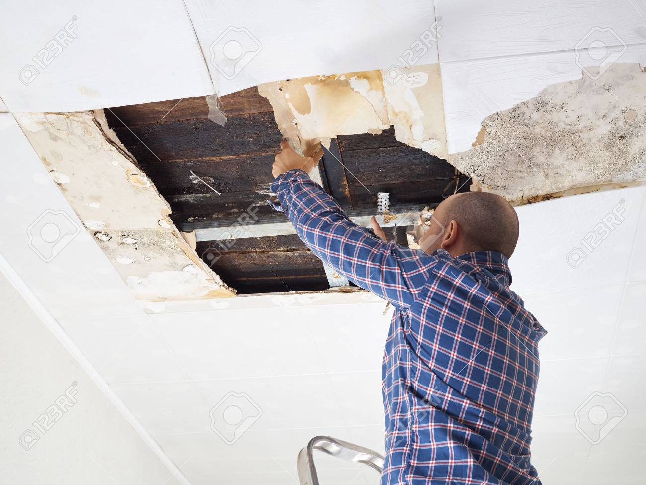 Man repairing collapsed ceiling. Ceiling panels damaged huge hole in roof from rainwater leakage.Water damaged ceiling . - 57035834 Man repairing collapsed ceiling. Ceiling panels damaged huge hole in roof from rainwater leakage.Water damaged ceiling . - 57035834