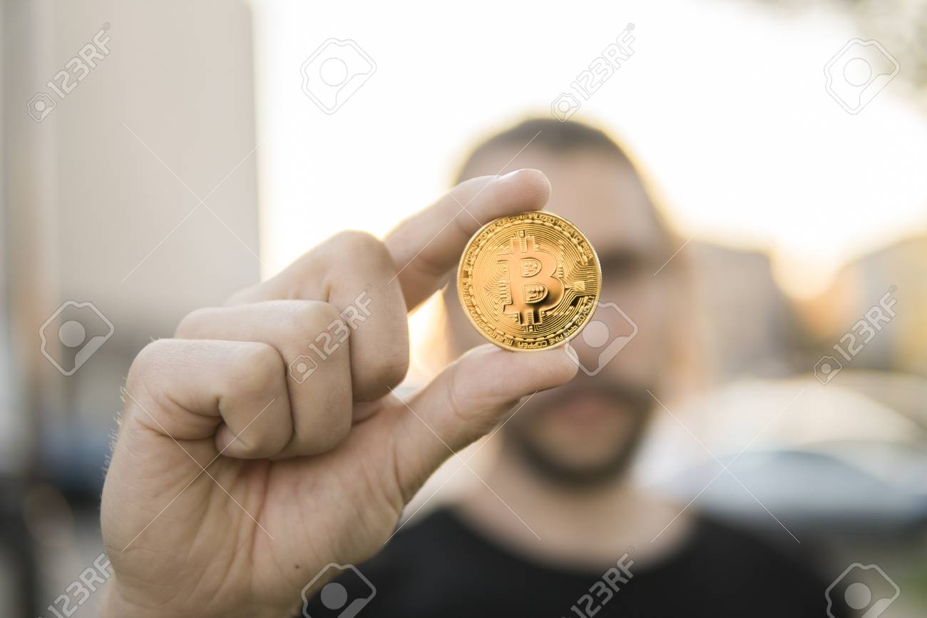 한 남자와 함께 흐릿한 일몰 배경에 있는 황금 비트코인 동전. 암호화 통화 가상 화폐를 손에 들고 있습니다. 비즈니스, 상업, 교환,  디지털 화폐. 로열티 무료 사진, 그림, 이미지 그리고 스톡포토그래피. Image 103967128