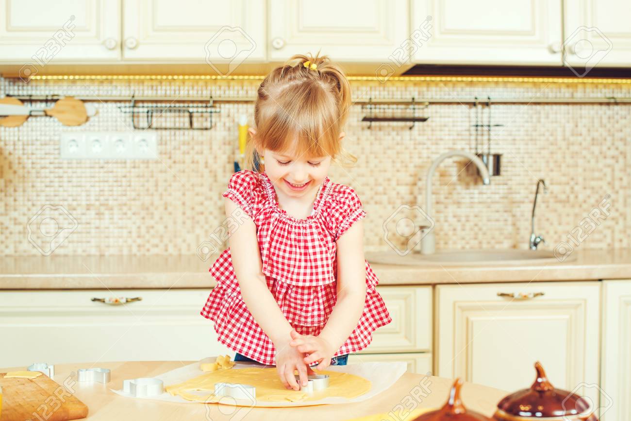 Cute Little Girl Helping Her Mother Bake Cookies In The Kitchen