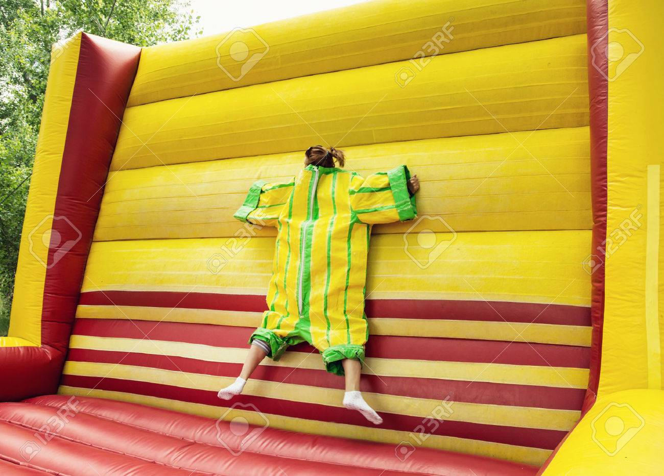 Young woman in plastic dress in a bouncy castle imitates a fly on velcro wall. Inflatable attraction. Leisure activity. - 53541227 Young woman in plastic dress in a bouncy castle imitates a fly on velcro wall. Inflatable attraction. Leisure activity. - 53541227