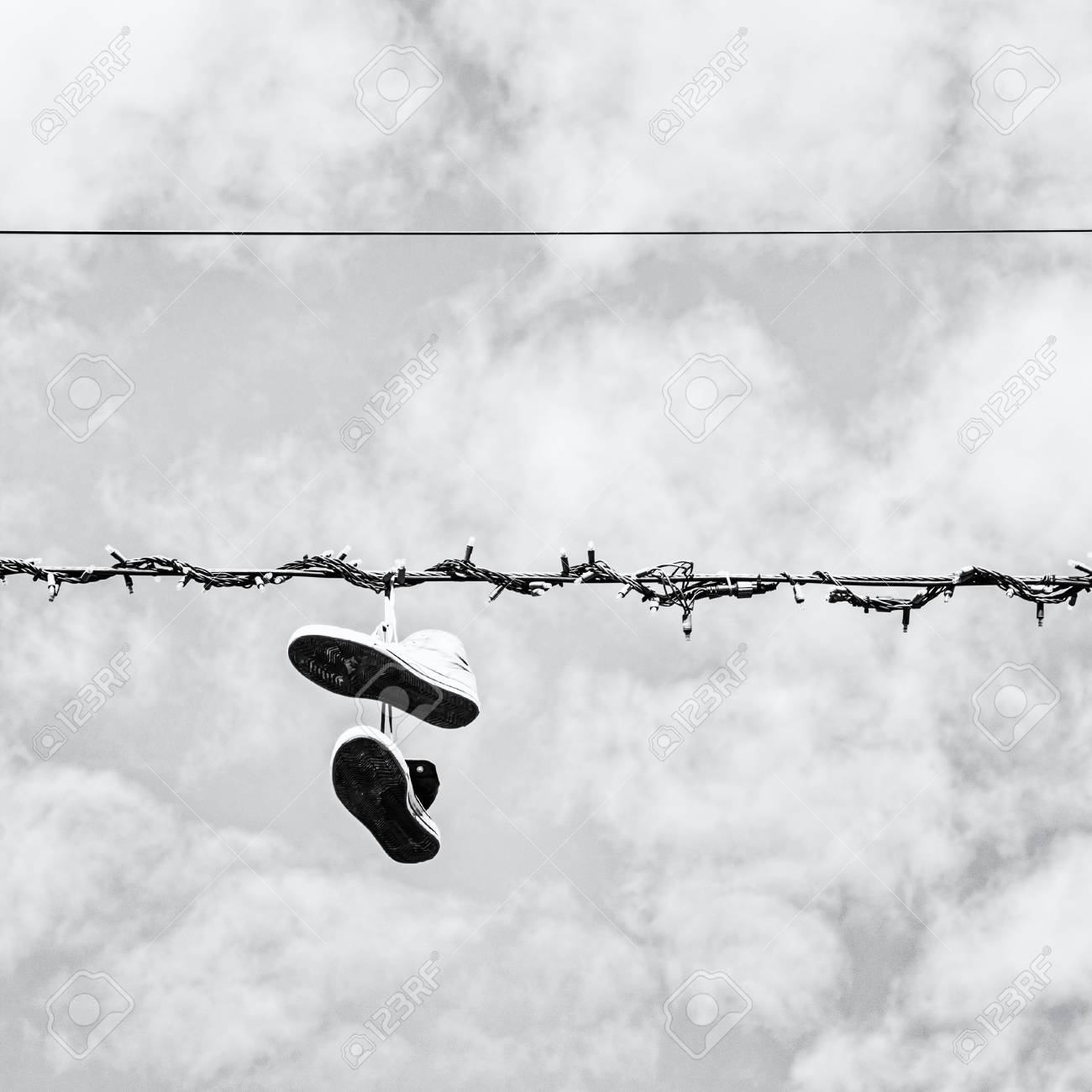 Sneakers hanging on the power line black and white photo bad joke stock