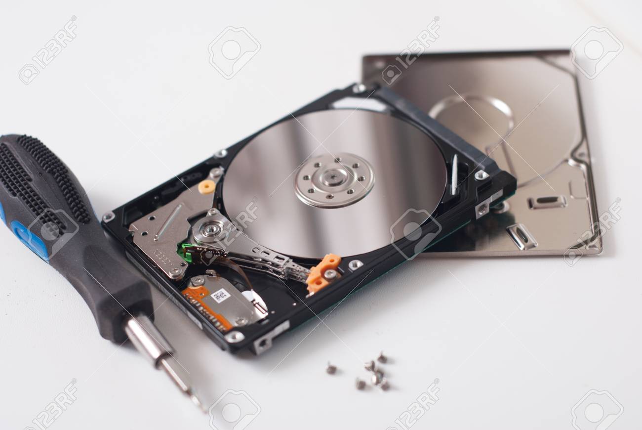 コンピューター Hdd ドライブ ミラー効果からハード ドライブを離れて取ったドライバー付きのゴム製ハンドルねじ明るい背景にネジを緩める の写真素材 画像素材 Image