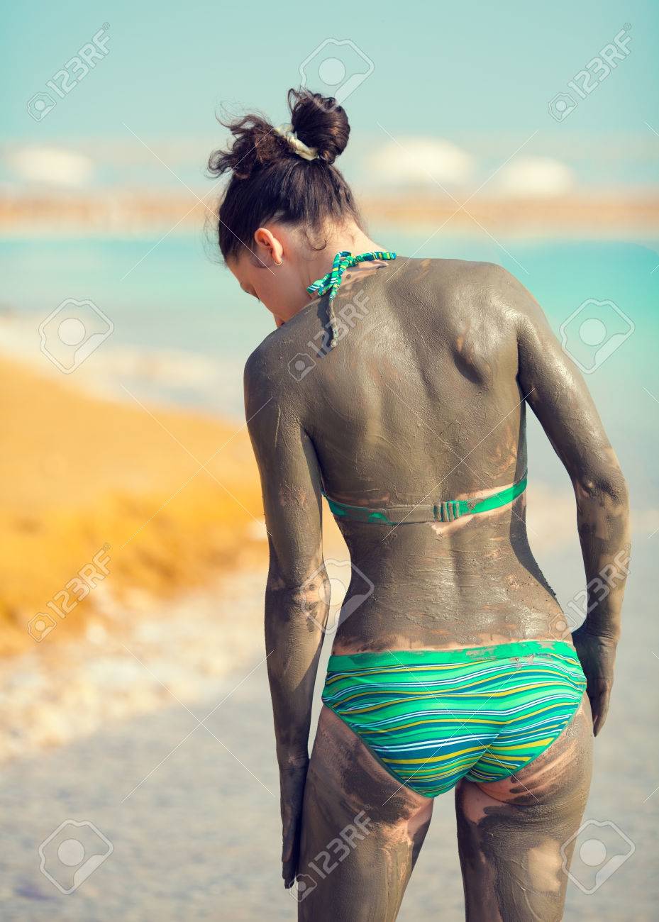 女性がカメラに戻ってビーチで泥にまみれてください の写真素材 画像素材 Image
