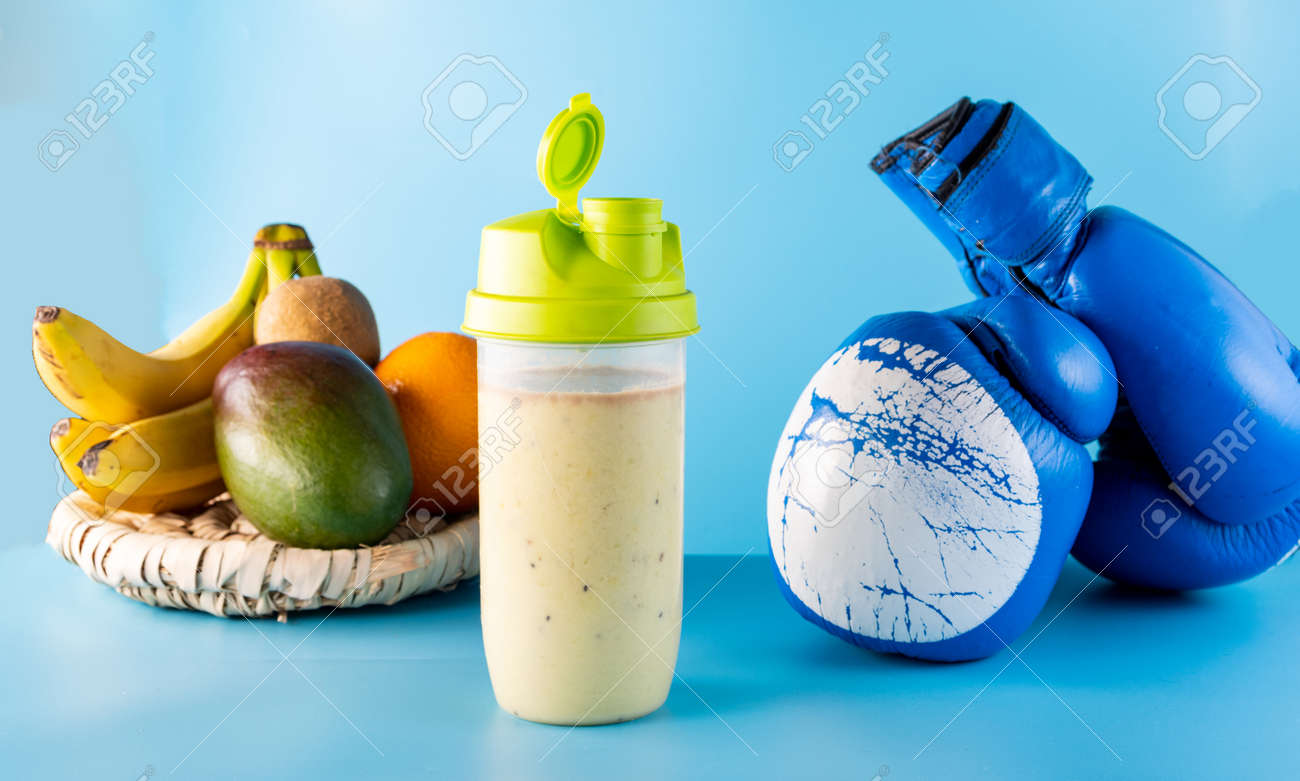 Vitamin protein sports nutrition. Multivitamin food from fruits. Milk cocktail and boxing gloves. Blue background. - 168666209 Vitamin protein sports nutrition. Multivitamin food from fruits. Milk cocktail and boxing gloves. Blue background. - 168666209