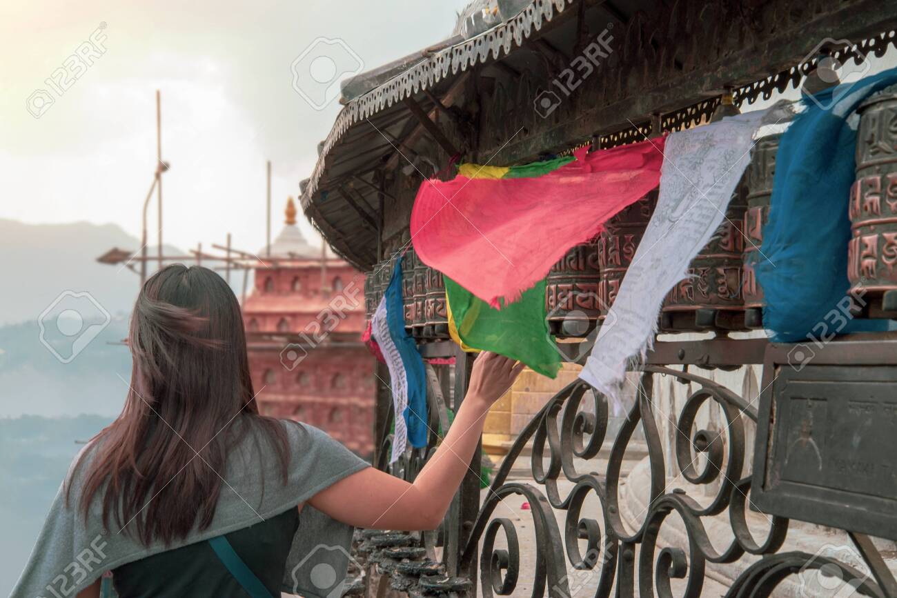Tibetan prayer wheels. A woman tourist rolling the prayer wheels at Swayambhunath, Nepal. Text translation: The magic symbol power of buddhism for prayer get divine blessings and good fortune - 128412552 Tibetan prayer wheels. A woman tourist rolling the prayer wheels at Swayambhunath, Nepal. Text translation: The magic symbol power of buddhism for prayer get divine blessings and good fortune - 128412552