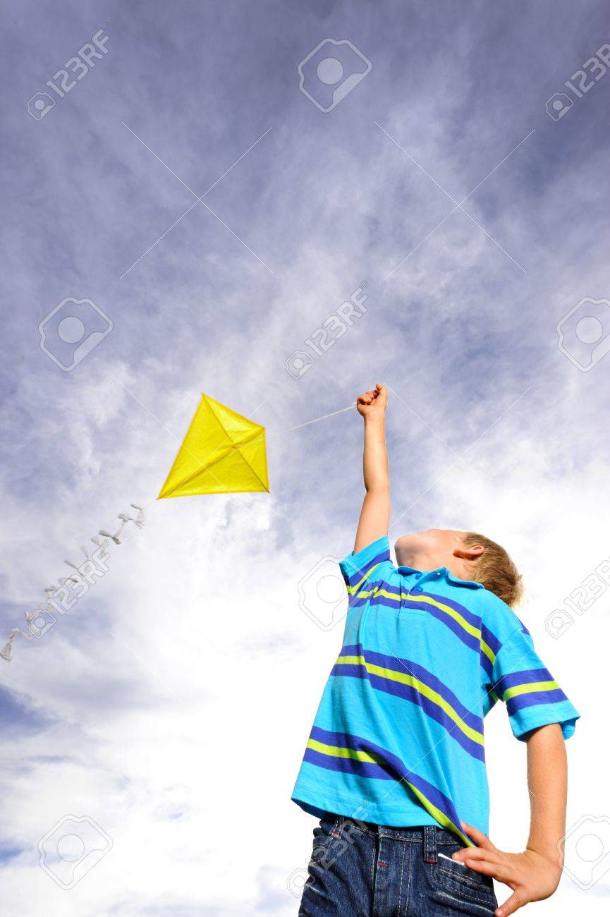Young boy flies a yellow kite on a windy summer day - 9967819 Young boy flies a yellow kite on a windy summer day - 9967819