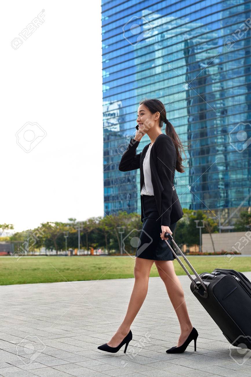 アジア中国語旅行携帯電話屋外現代都市で歩道に沿って歩いてスーツケース バッグを引っ張るビジネス女性 の写真素材 画像素材 Image 40834515
