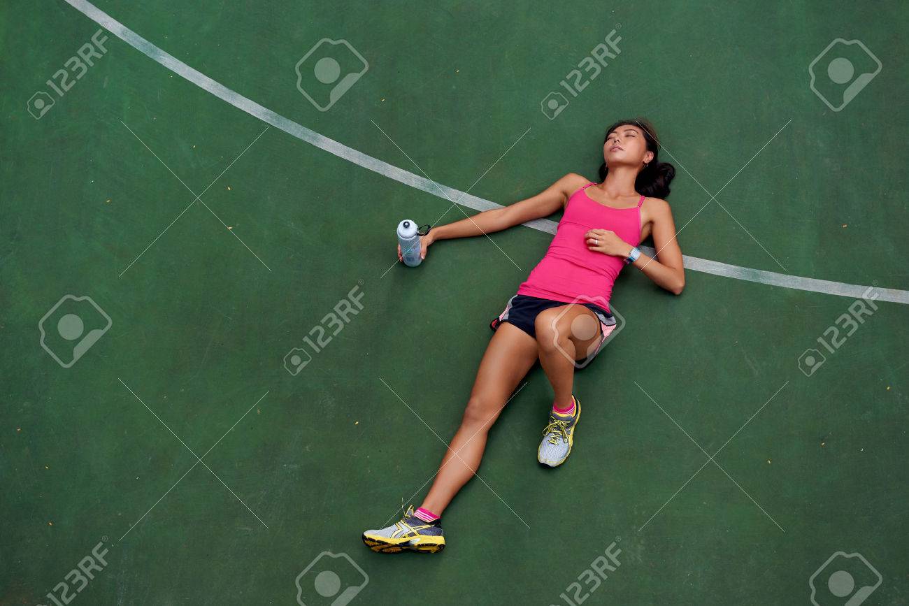 exhausted sporty woman runner laying on basketball court after fitness running workout outdoors - 40834432 exhausted sporty woman runner laying on basketball court after fitness running workout outdoors - 40834432