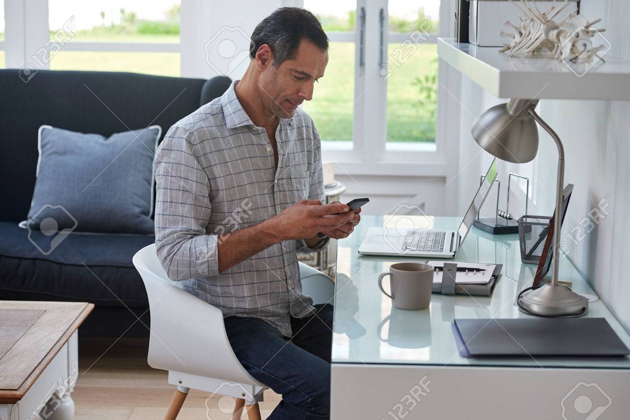 Ltere Schöner Mann Auf Mobilen Handy Suchen, Während Zu Hause In ... Ltere Schöner Mann Auf Mobilen Handy Suchen, Während Zu Hause In ...