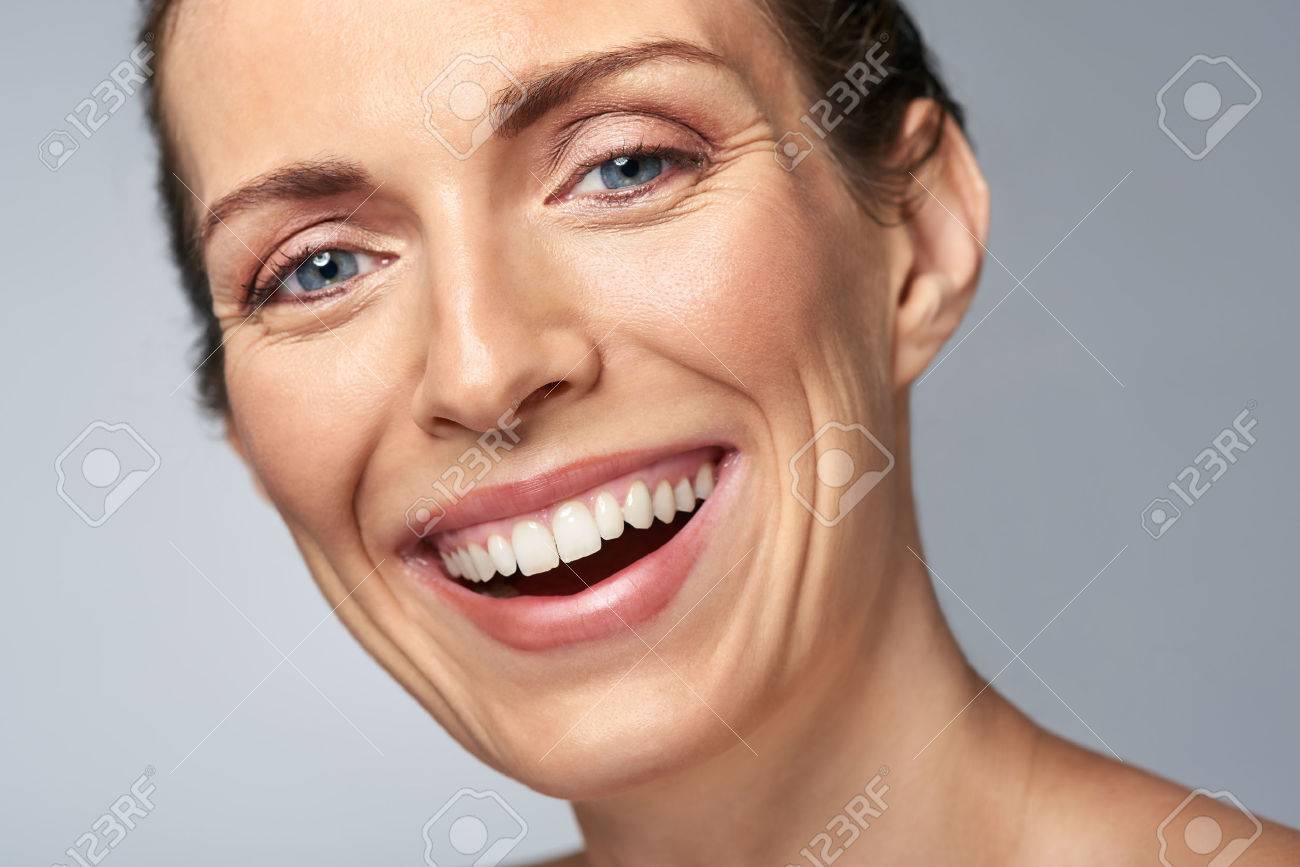 Happy laughing middle age woman in studio, isolated on grey - 57346979 Happy laughing middle age woman in studio, isolated on grey - 57346979