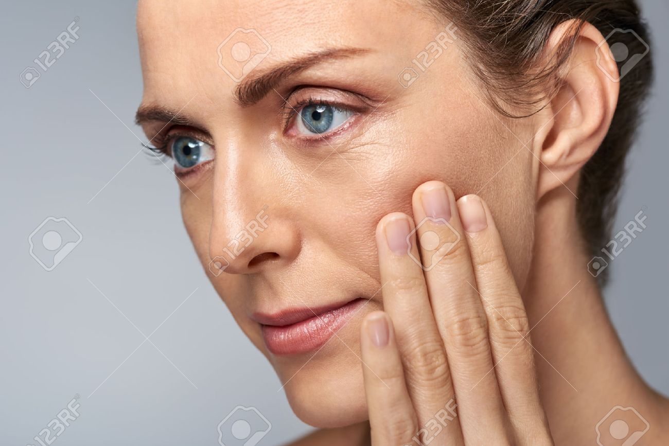 Attractive middle aged woman touching her cheek skin, mature beauty concept - 57346982 Attractive middle aged woman touching her cheek skin, mature beauty concept - 57346982