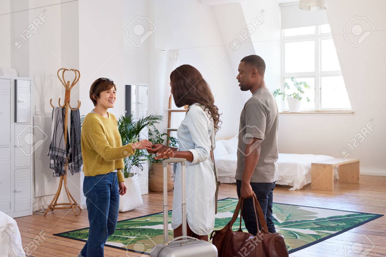 Asian woman welcomes black couple into her house home accommodation for their holiday vacation trip - 83861754 Asian woman welcomes black couple into her house home accommodation for their holiday vacation trip - 83861754