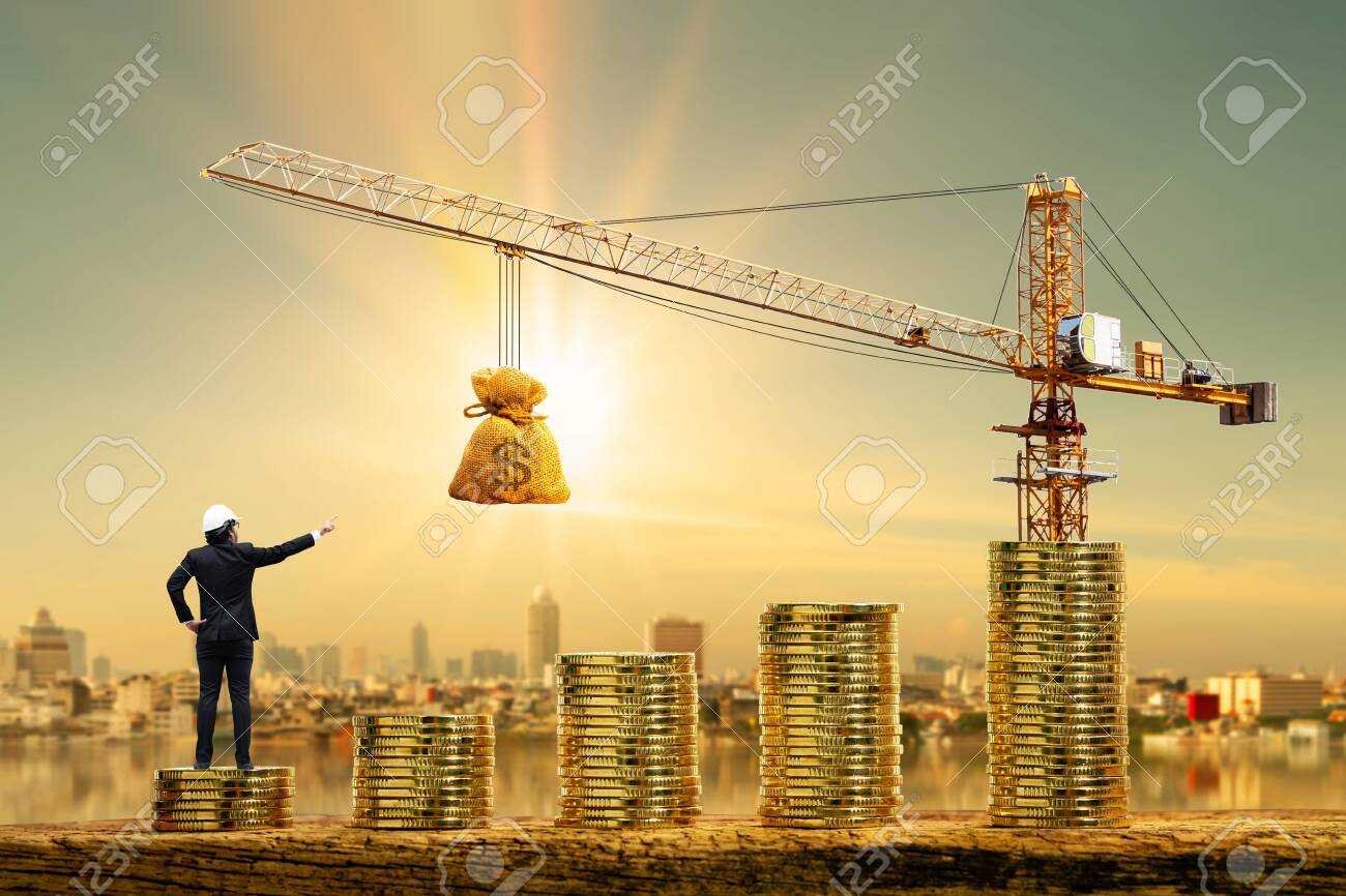 Os engenheiros do homem estão trabalhando na moeda de ouro da pilha com valor de crescimento e guindaste de torre e freio de elevação com saco de dinheiro no fundo da paisagem urbana do borrão da foto, empréstimo e orçamento para o conceito imobiliário da construção. - 153527079 Os engenheiros do homem estão trabalhando na moeda de ouro da pilha com valor de crescimento e guindaste de torre e freio de elevação com saco de dinheiro no fundo da paisagem urbana do borrão da foto, empréstimo e orçamento para o conceito imobiliário da construção. - 153527079
