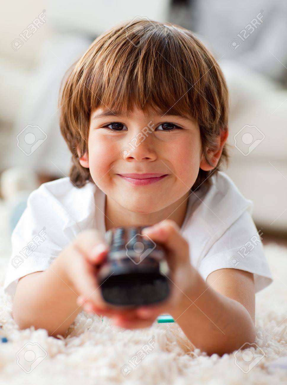 Smiling little boy watching TV lying on the floor - 10107114 Smiling little boy watching TV lying on the floor - 10107114