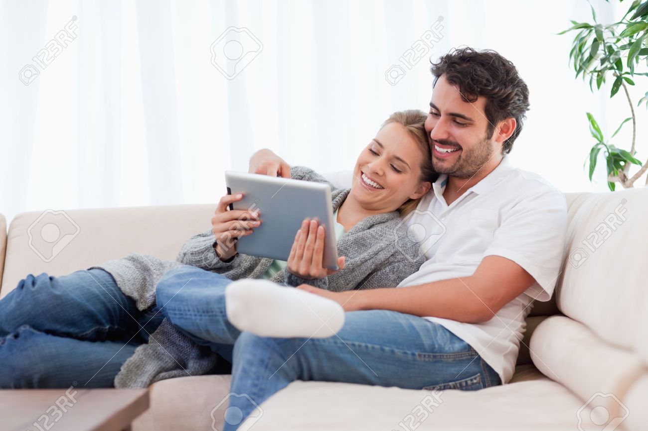 In love couple using a tablet computer in their living room - 11684846 In love couple using a tablet computer in their living room - 11684846