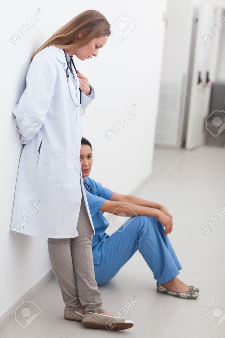 Doctor Standing Next To A Nurse Sitting On The Floor In Hospital