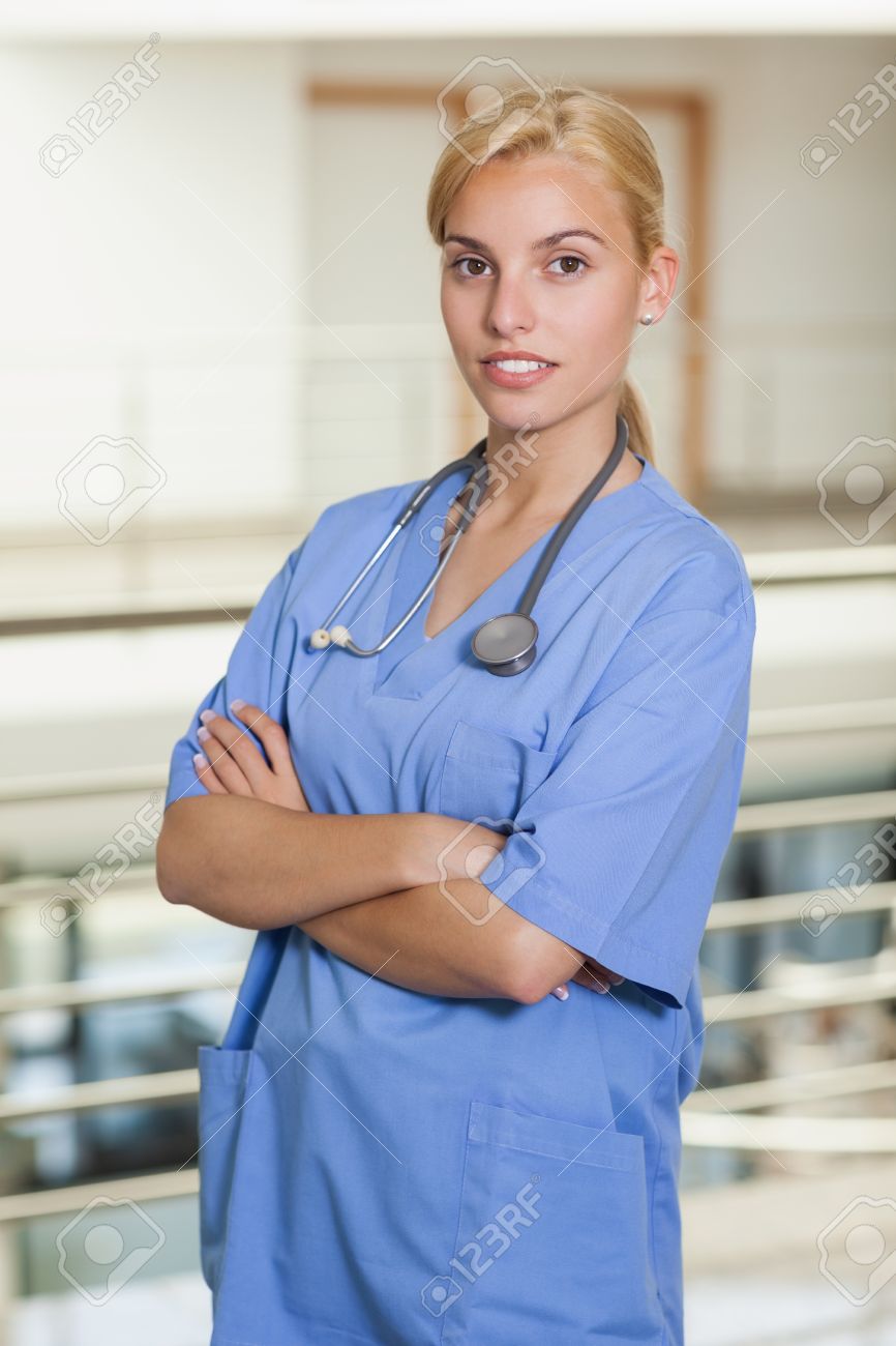 blonde nurse with arms crossed in hospital corridor stock photo