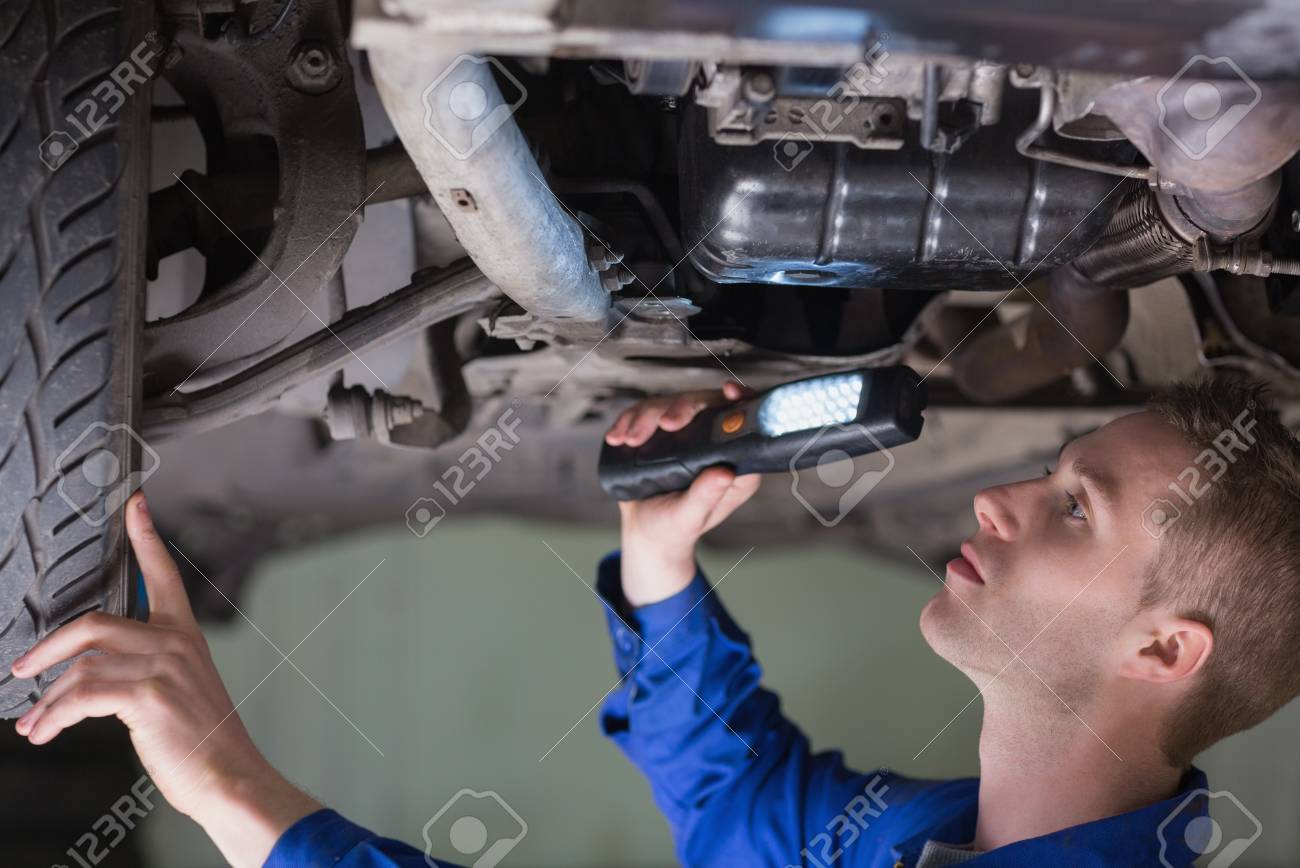 young mechanic examining car using flashlight stock photo picture