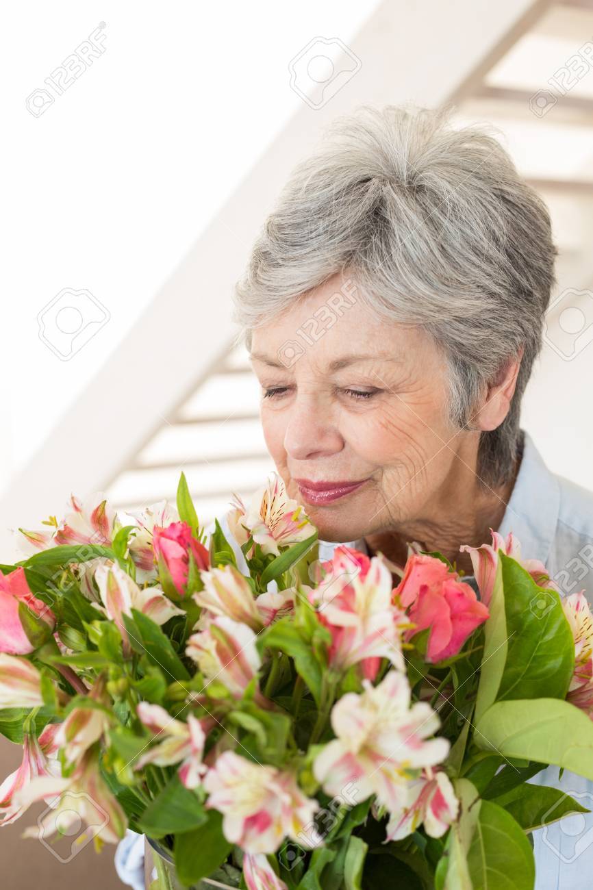 Femme A La Retraite A Respirer Son Bouquet De Fleurs A La Maison Dans Le Salon Banque D Images Et Photos Libres De Droits Image