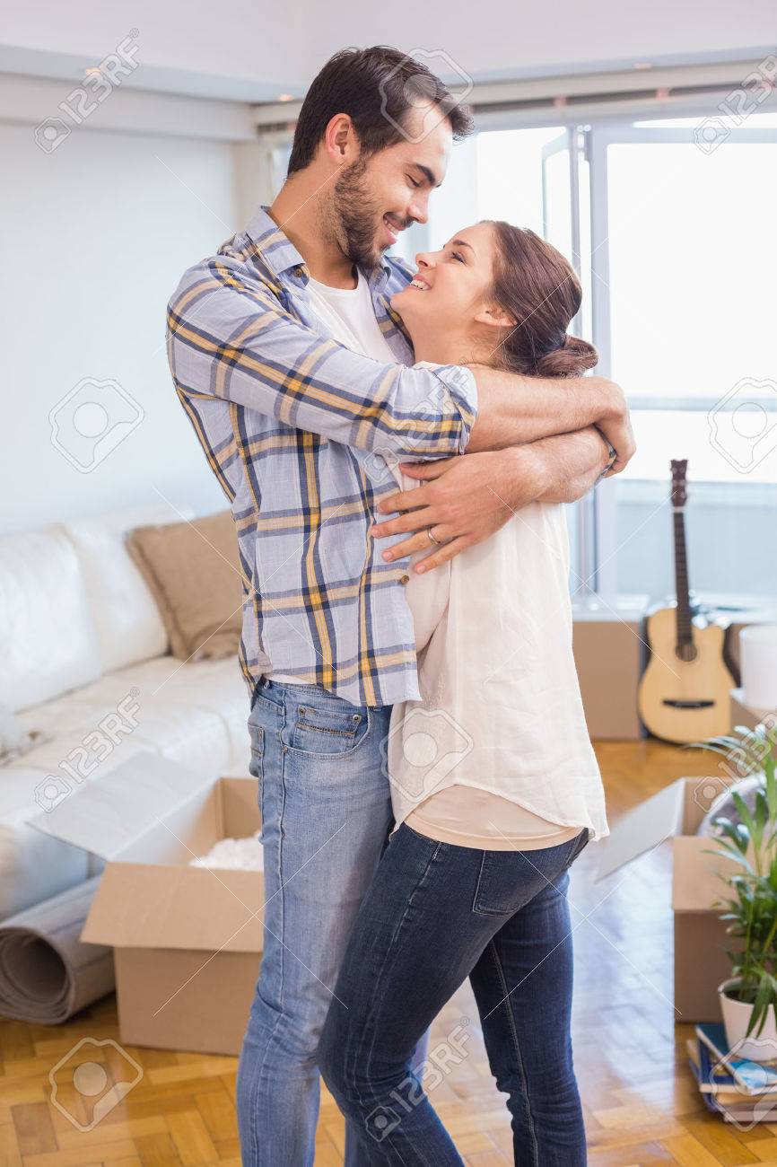 Cute Couple Hugging And Smiling In Their New Home Stock Photo ...