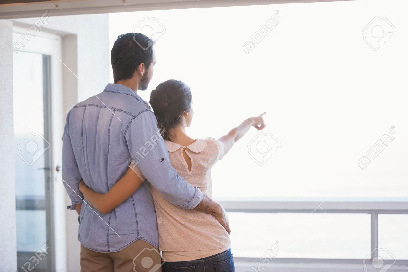 お似合いのカップルが彼らの新しい家の窓の外見て の写真素材 画像素材 Image