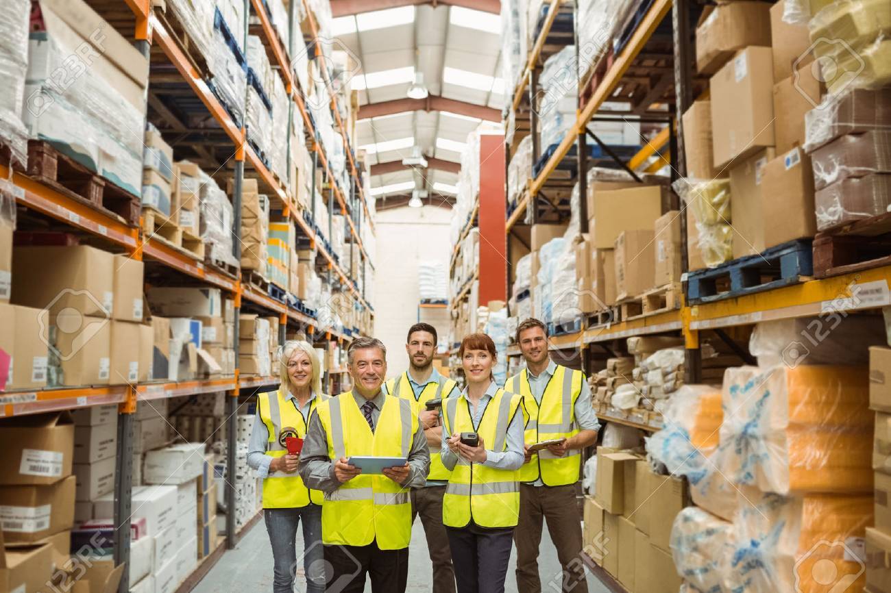 smiling warehouse team looking at camera in a large warehouse stock