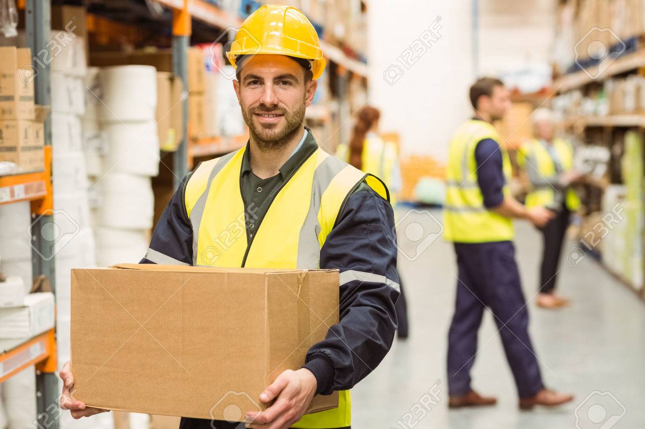 warehouse worker smiling at camera carrying a box in a large stockstock photo warehouse worker smiling at camera carrying a box in a large warehouse