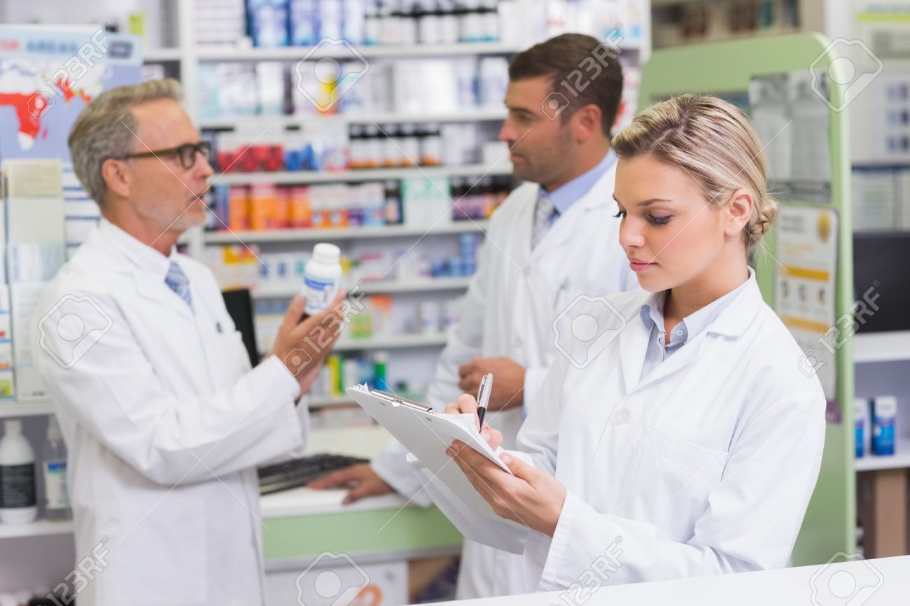 Focused Pharmacist Writing On Clipboard At The Hospital Pharmacy ...