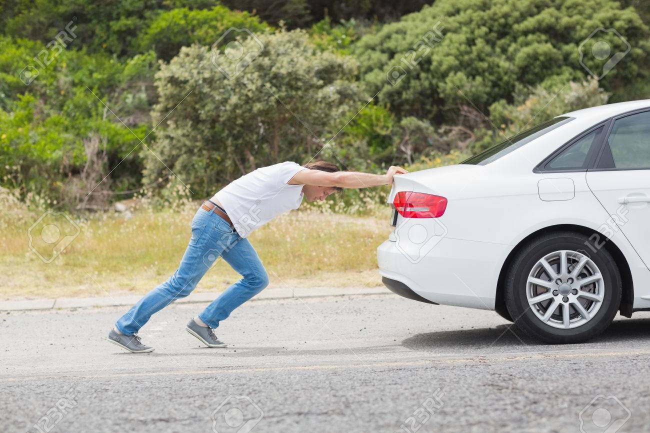 man pushing his car at the side of the road stock photo picture and