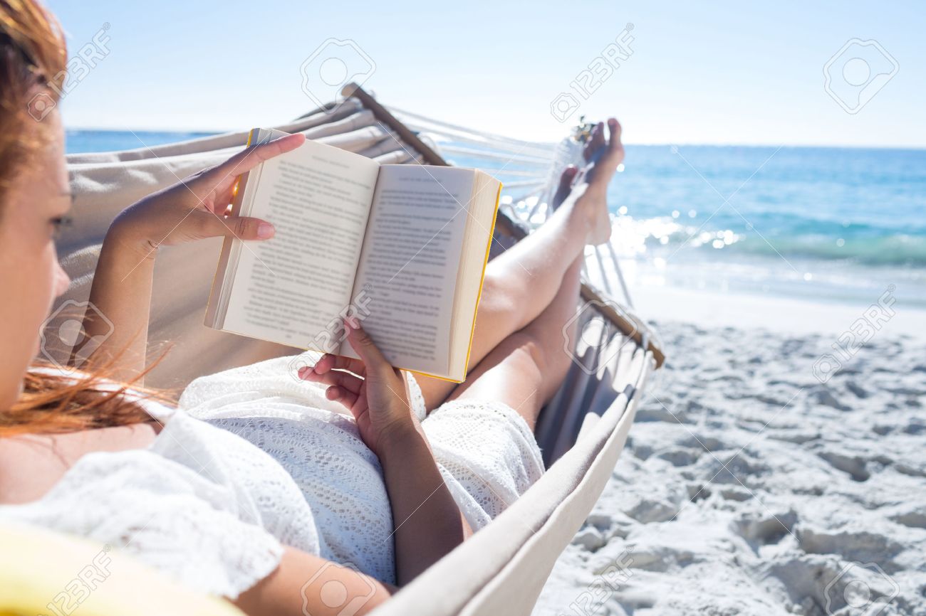brunette reading a book while relaxing in the hammock at the stock
