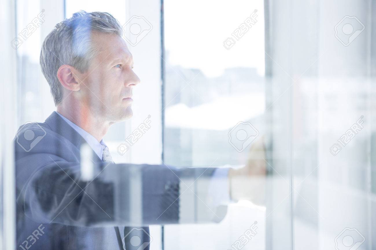 Thinking businessman in the office looking through the window - 46066928 Thinking businessman in the office looking through the window - 46066928