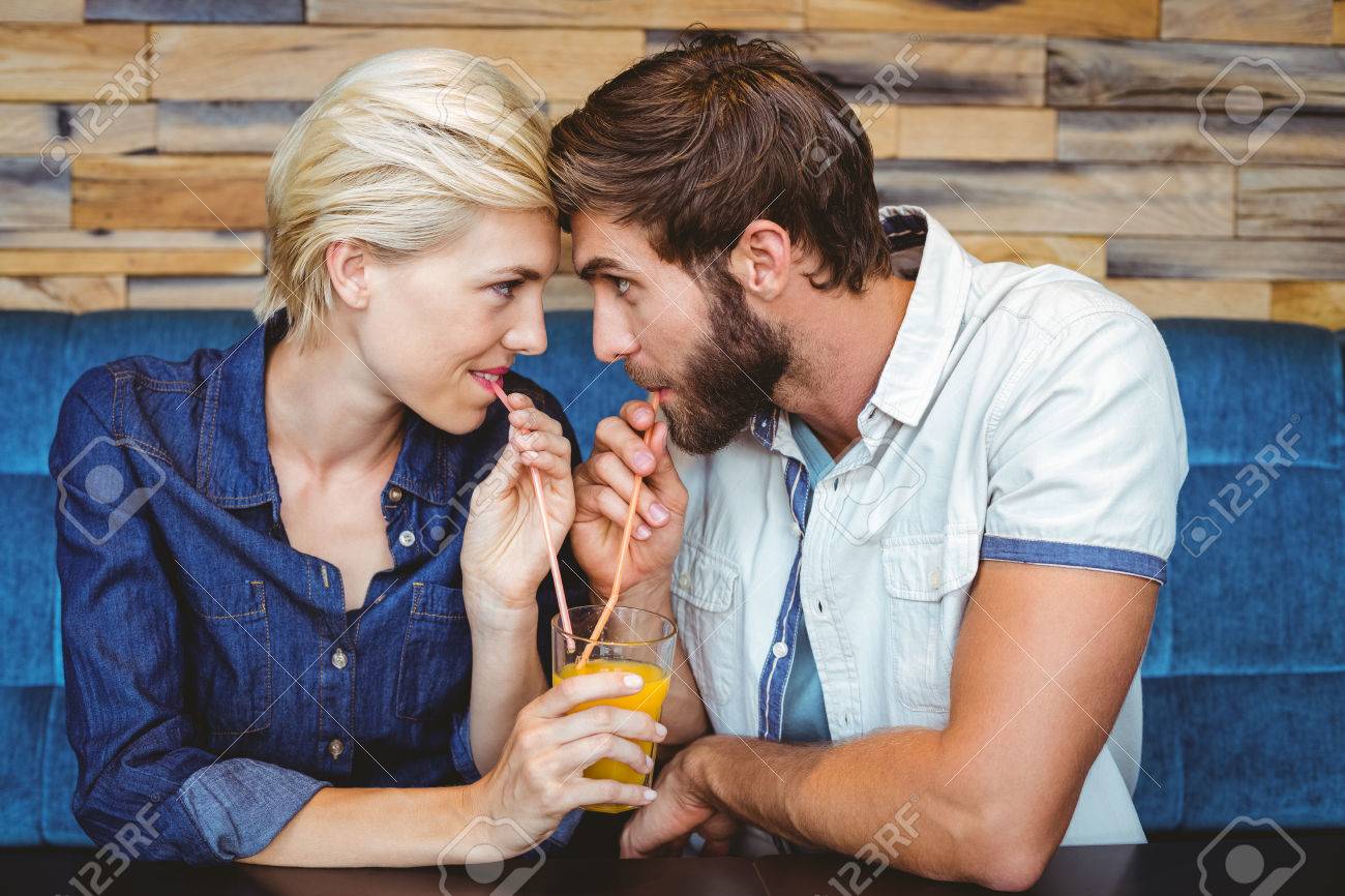 カフェでオレンジ ジュースのガラスを共有の日にお似合いのカップル の写真素材 画像素材 Image