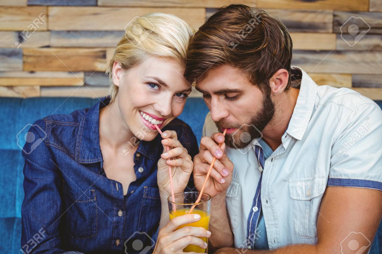 カフェでオレンジ ジュースのガラスを共有の日にお似合いのカップル の写真素材 画像素材 Image