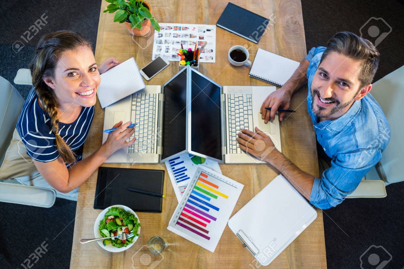 Lächelnde Partner Arbeitet Am Schreibtisch Mit Laptop Im Büro ... Lächelnde Partner Arbeitet Am Schreibtisch Mit Laptop Im Büro ...