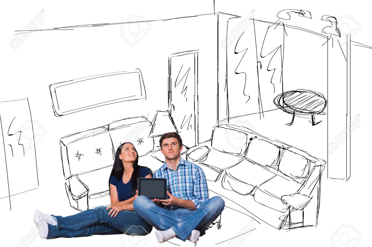 Young Couple Sitting On Floor With Tablet Against Living Room