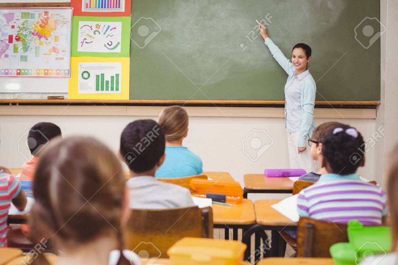 teacher teaching a lesson in class at the elementary school stock