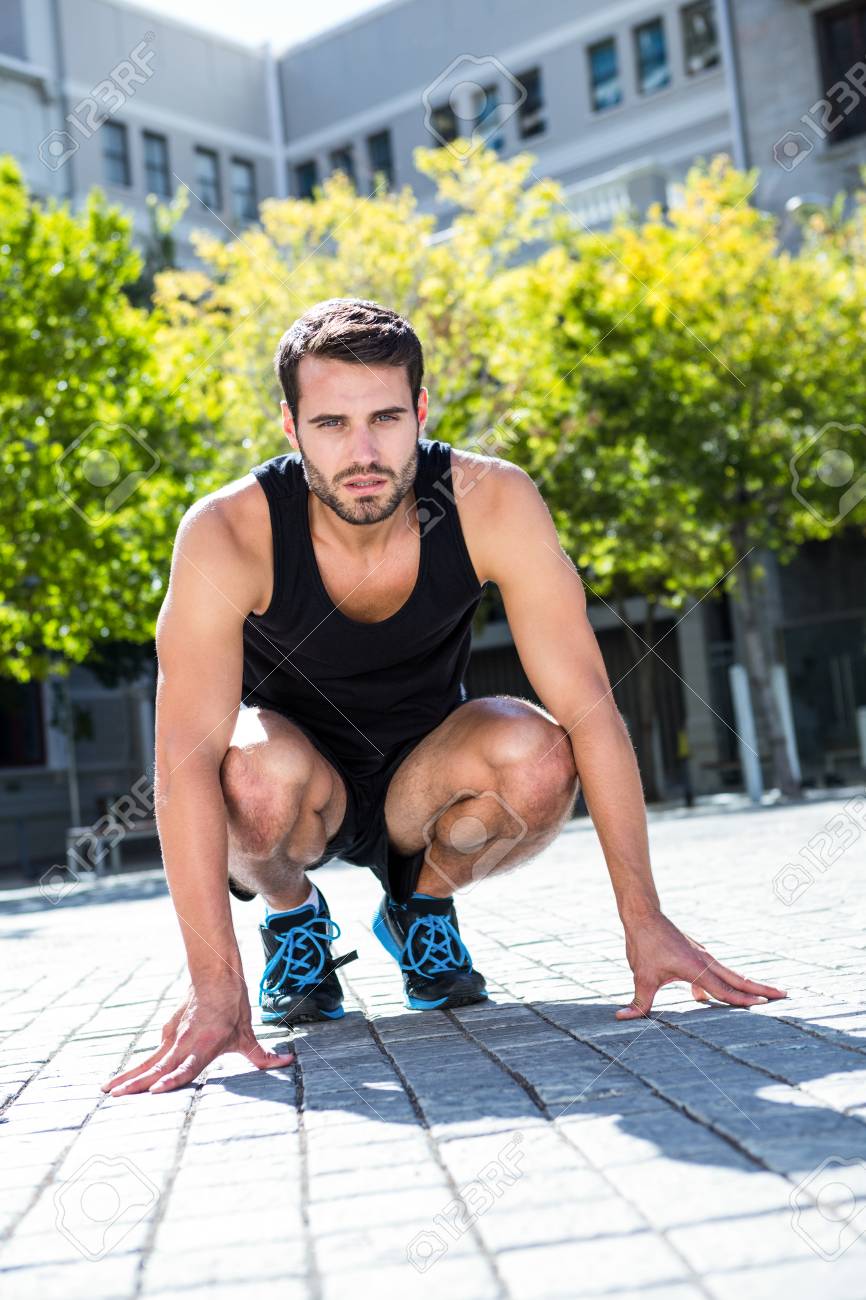 晴れた日にしゃがむ姿勢でハンサムなアスリートの肖像 の写真素材 画像素材 Image