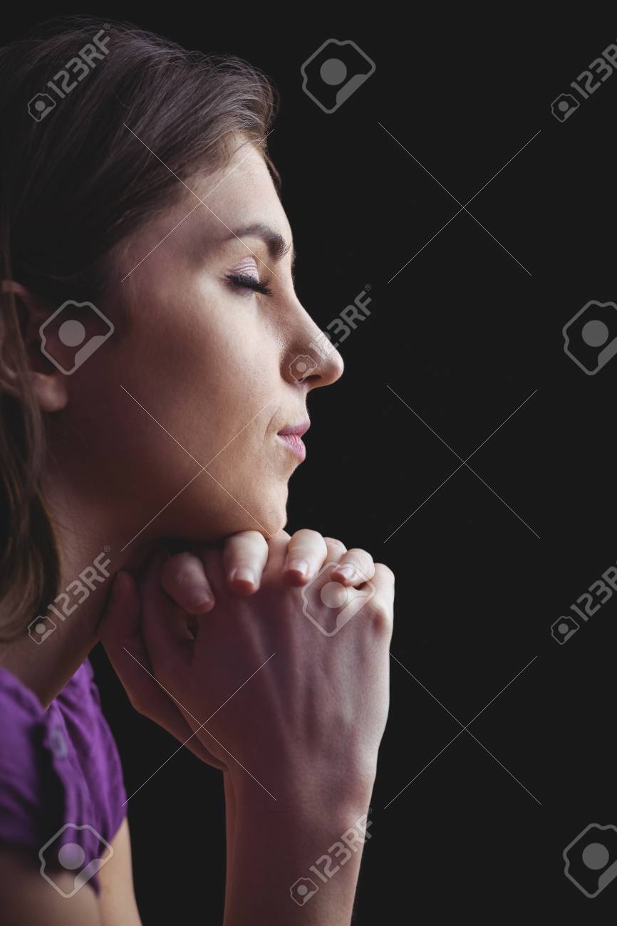 woman praying with hands together on black background stock photo
