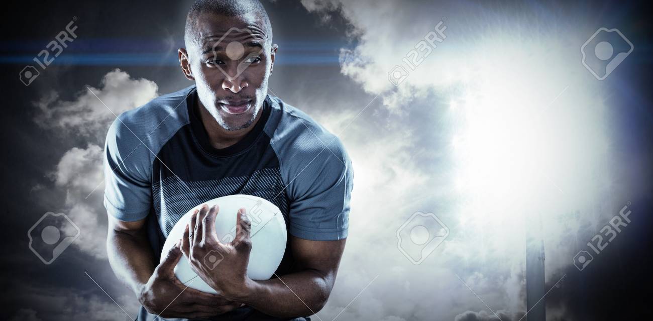 空のスポット ライトに対してボールをキャッチしながら笑みを浮かべてラグビー選手 の写真素材 画像素材 Image